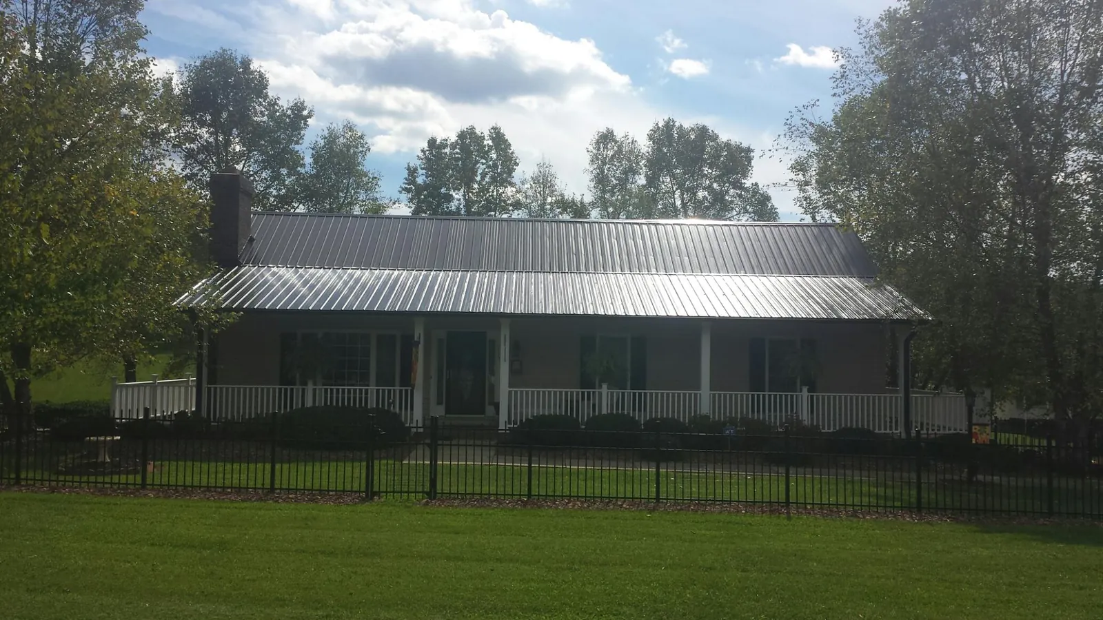 Gray metal roof on a brick ranch with a full width front porch — Gutter Guard Installation work by our crew in Port Jervis
