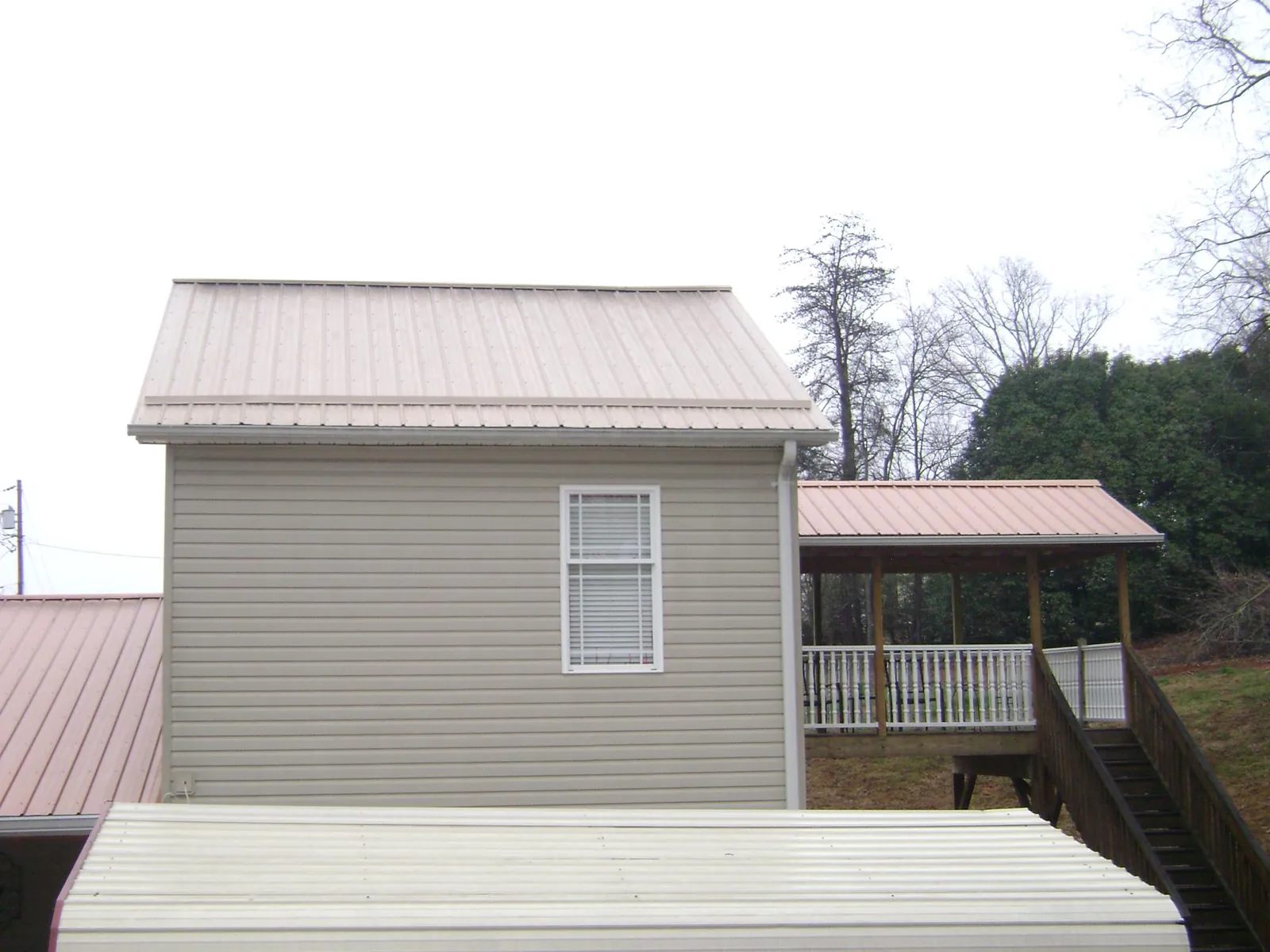 Tan metal roofs on a two story addition and attached porch, from a Roof Replacement job in Port Jervis