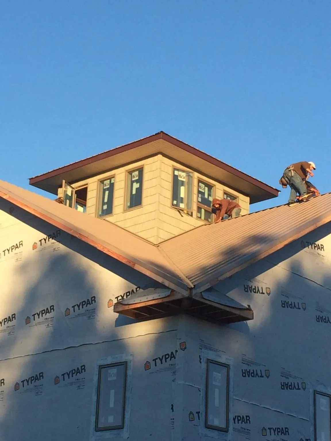 Roofers working around a rooftop cupola on a new metal roof at sunset — Roof Waterproofing in Port Jervis by Roofing Brothers